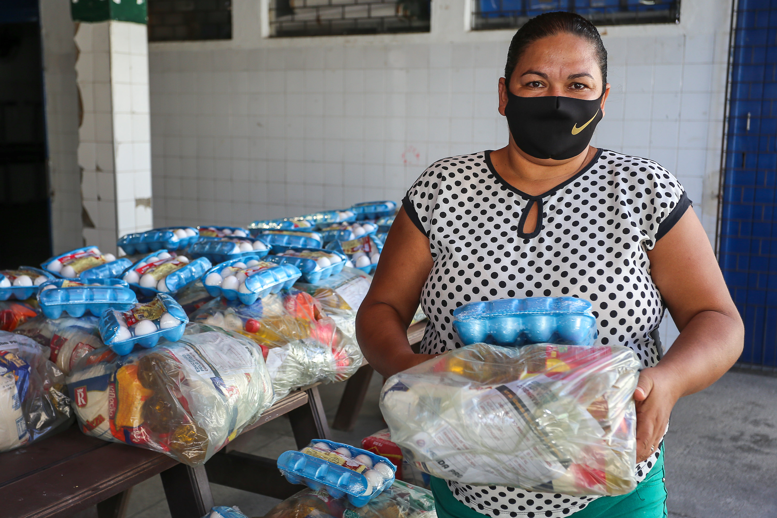 senhora usando máscara e posando para a foto segurando kit de alimentação